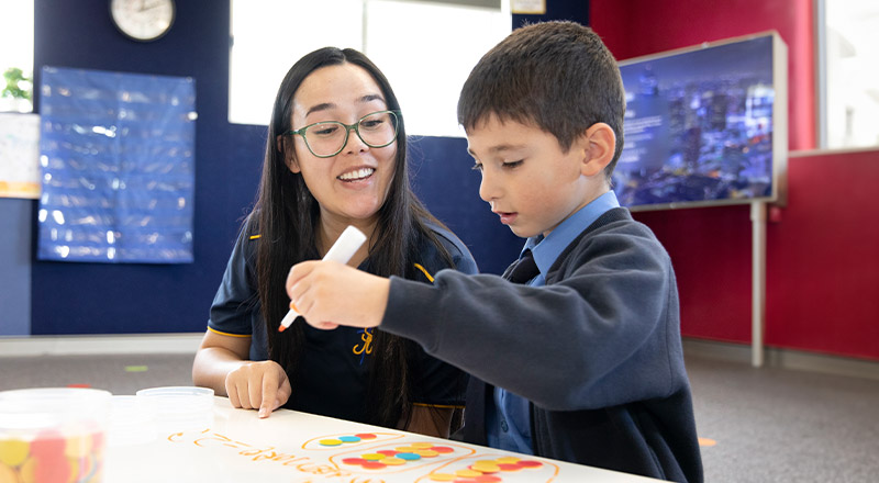 Student learning maths with his teacher in the classroom at St Michael's Primary School Blacktown South