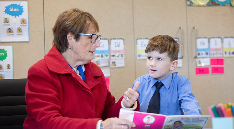 Student reading with his teacher in the classroom at St Michael's Primary School Blacktown South