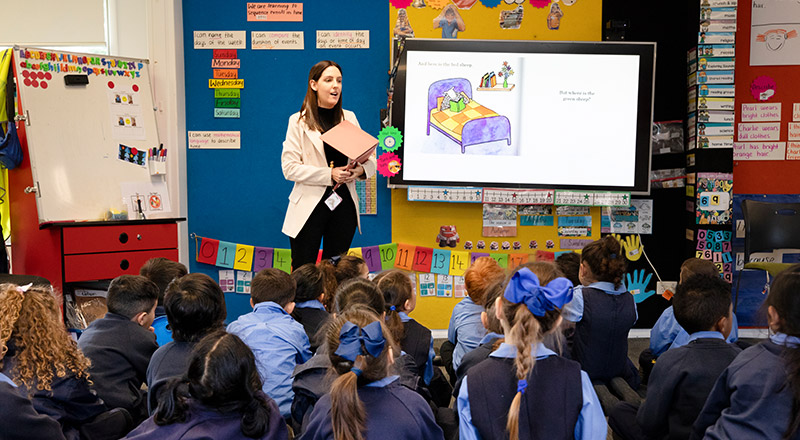 Teacher in front of her class reading with them at St Michael's Primary School Blacktown South
