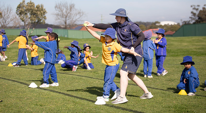 Students learning how to throw a ball on the school oval at St Michael's Primary School Blacktown South