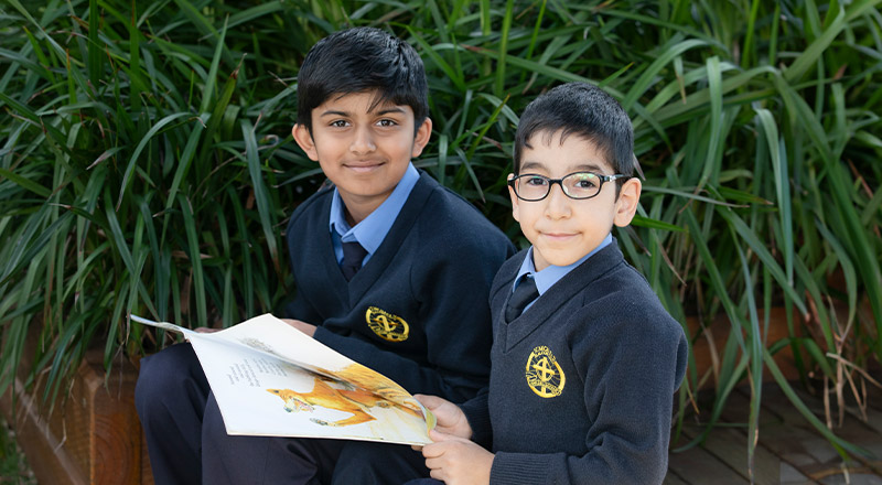 Students reading a book together in the playground at St Michael's Primary School Blacktown South
