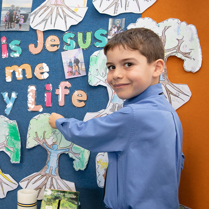 Student hanging an artwork in religion class at St Michael's Primary School Blacktown South