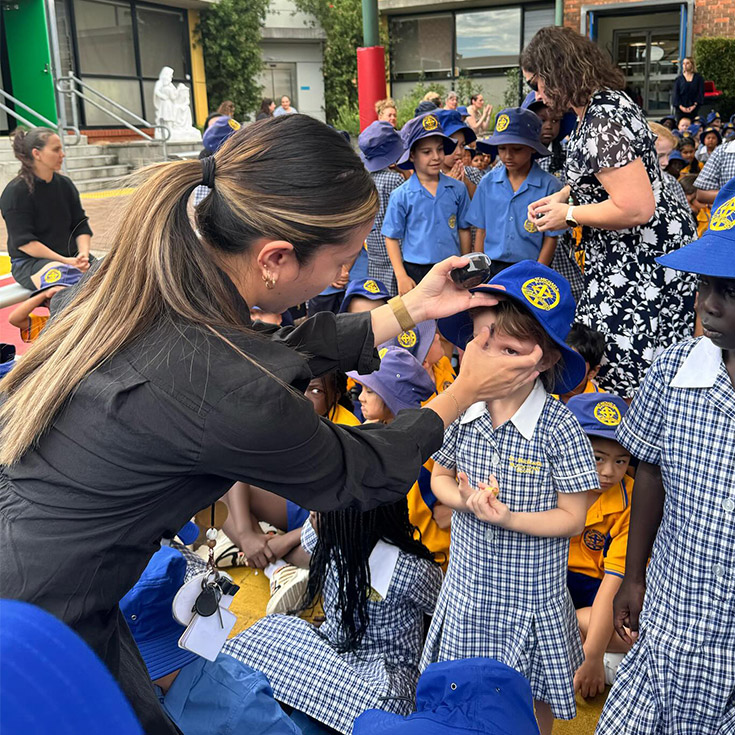 Student placing a cross on the forehead of a student on Ash Wednesday at St Michael's Primary School Blacktown South