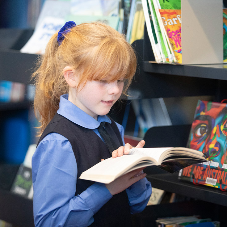 Student reading a book in the school library at St Michael's Primary School Blacktown South