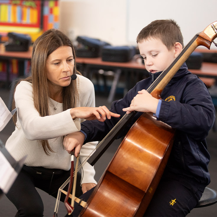 Student getting taught how to play the cello by his teacher at St Michael's Primary School Blacktown South